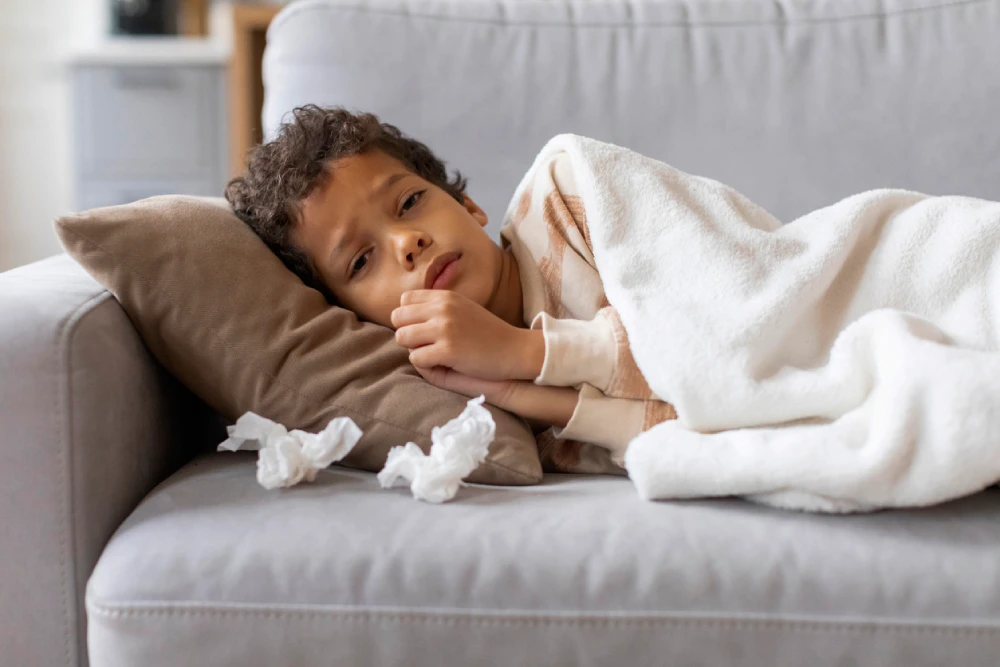 child with the flu resting on the couch