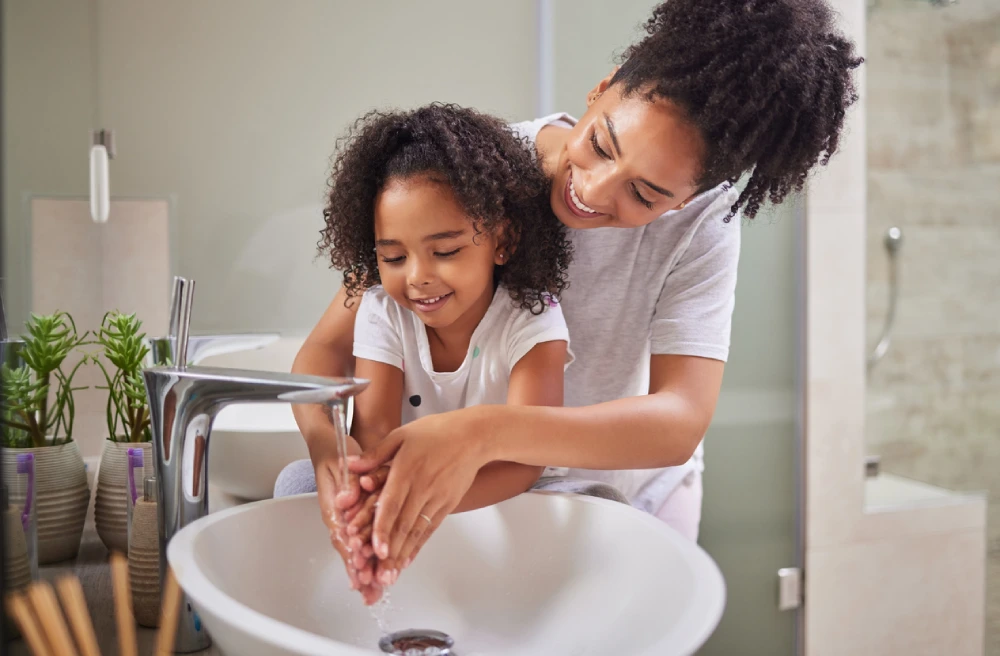 mother helping daughter wash her hands