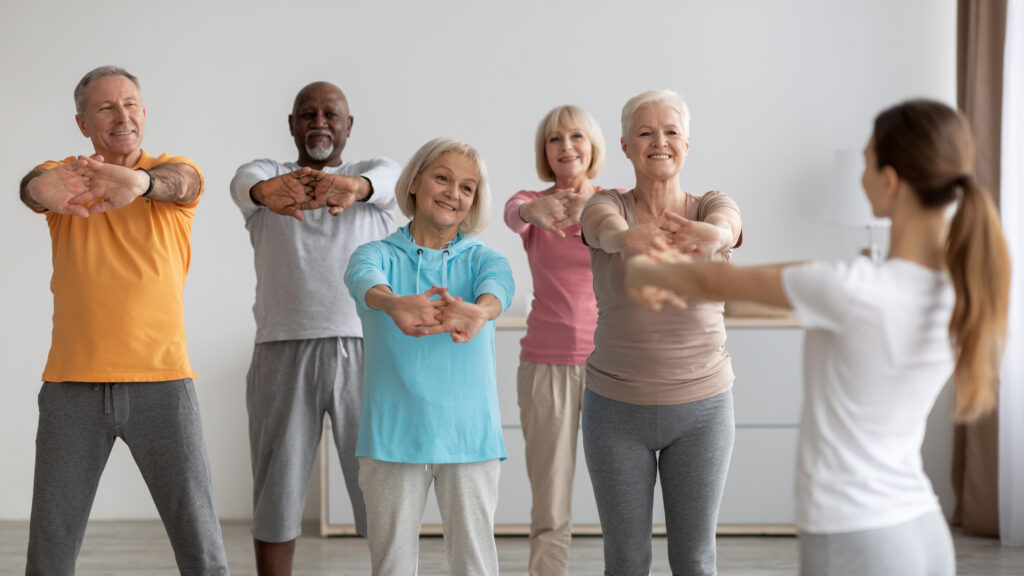 A diverse group of healthy seniors stand together in a fitness class. 