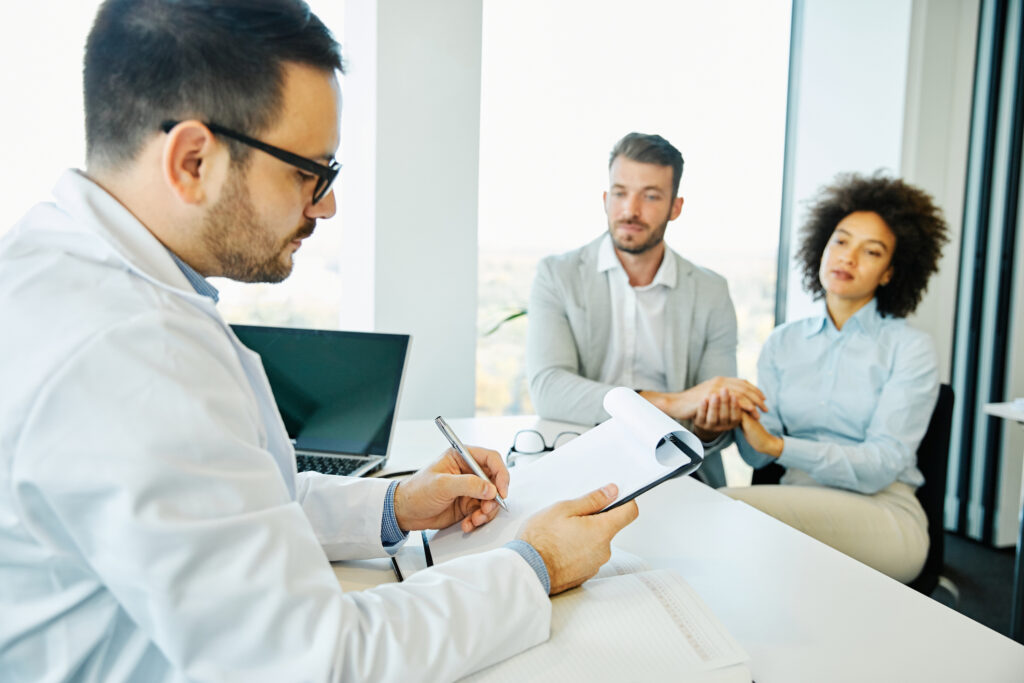 A male doctor gives results to a husband and wife. 