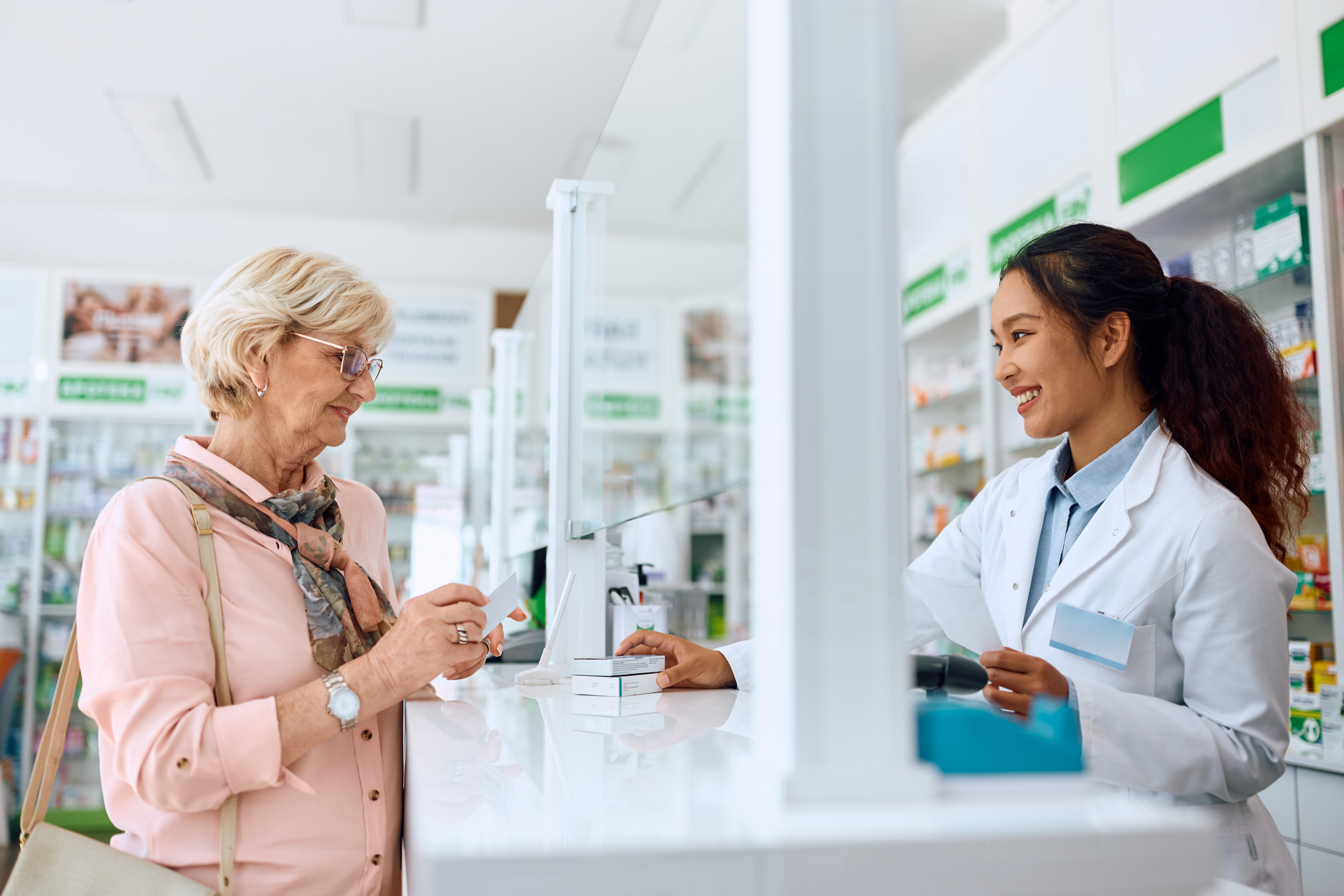 A older woman speaks with a female pharmacist at the pharmacy counter