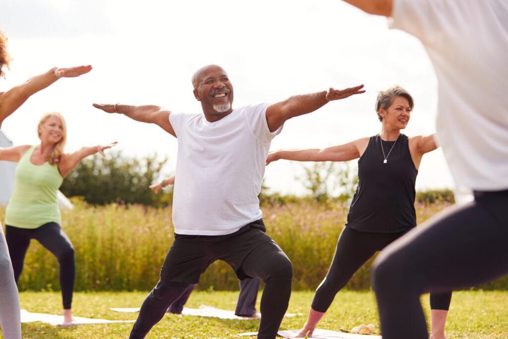 A group of older men and women stretch during an outdoor fitness class.