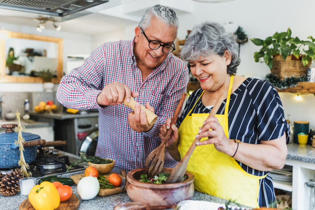 A senior couple is preparing a healthy meal in the kitchen. 