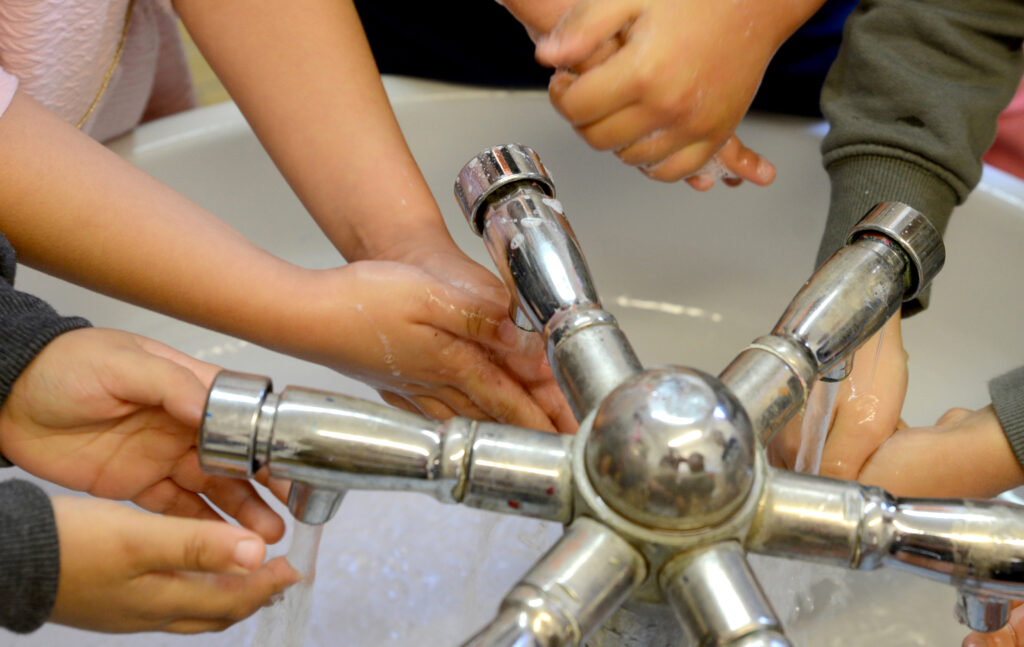 Children wash their hands in a communal sink at a primary school