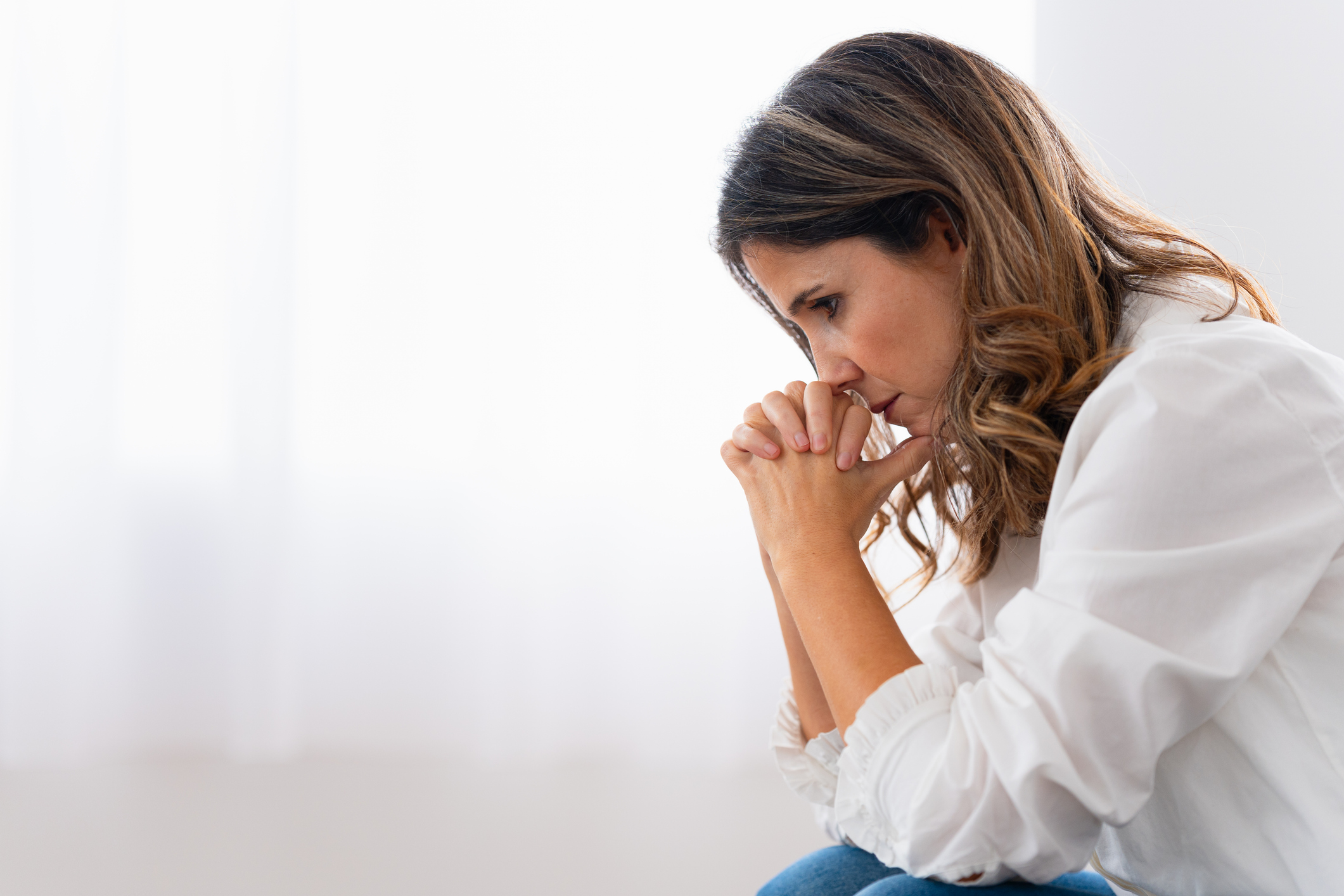 A woman appears sad as she sits resting her face on her hands.