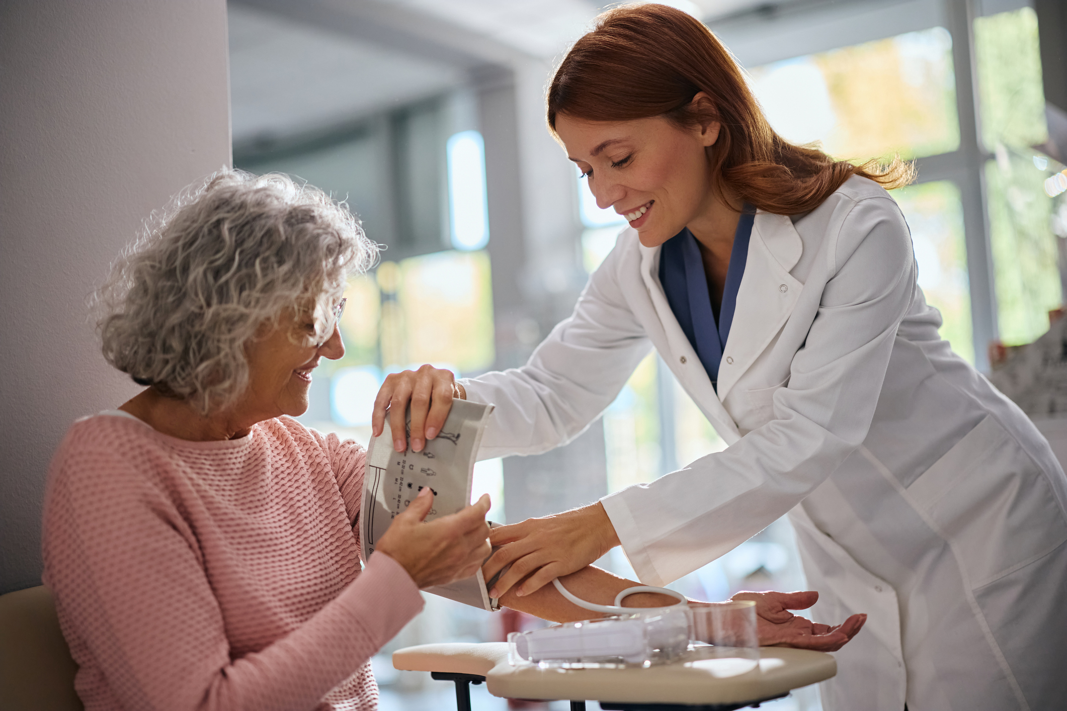 Une femme âgée se fait prendre la tension par une pharmacienne.