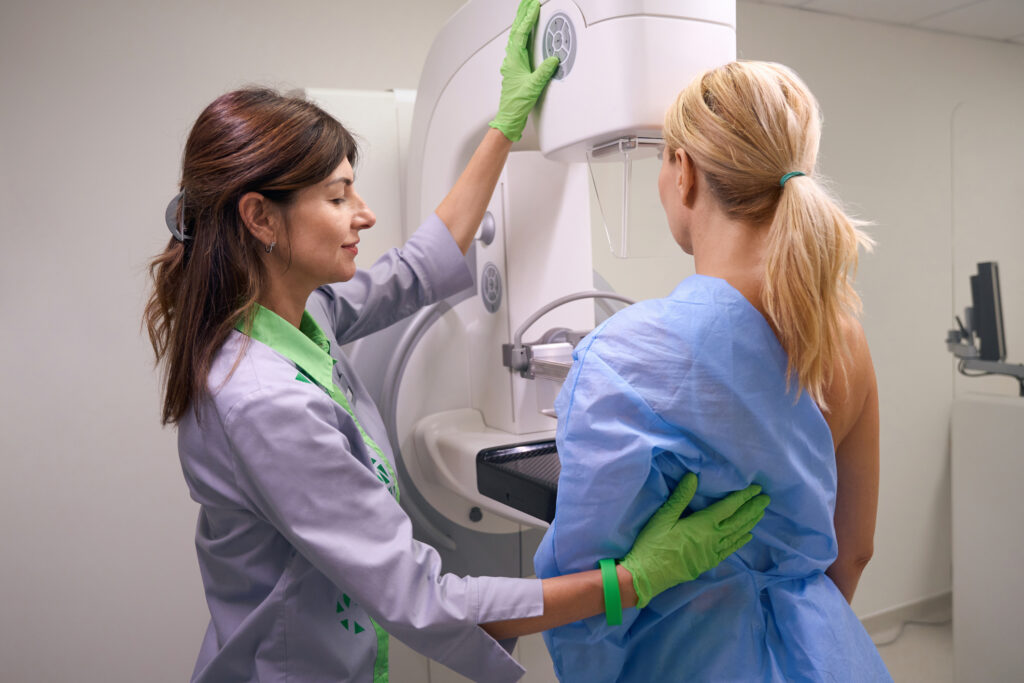 A technician positions a woman at the mammogram machine. 